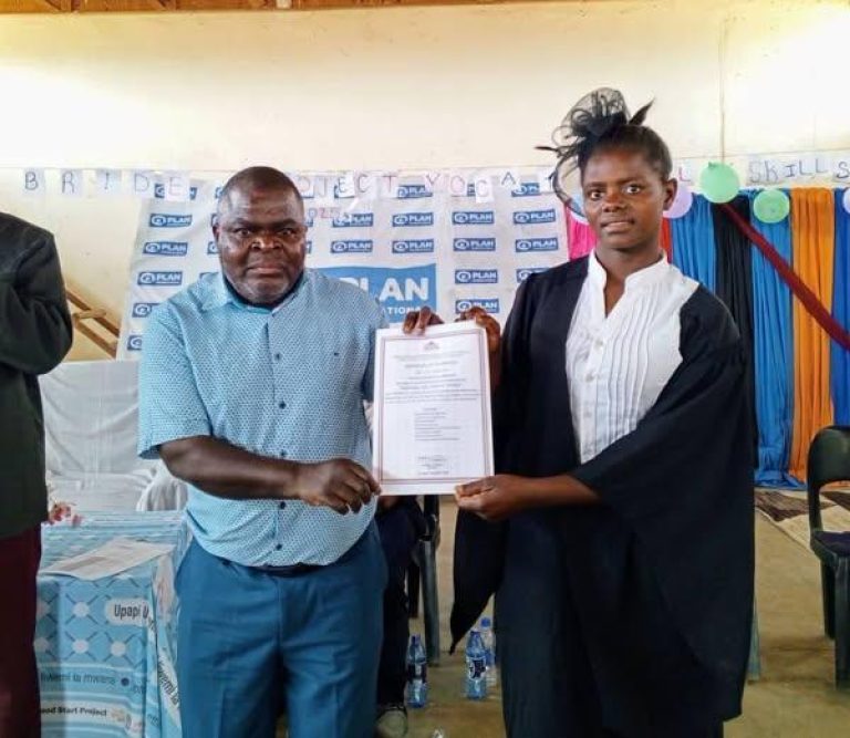 Chikuni L hands over a certificate to a trainee